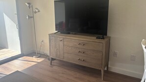 Et værelse med et træskab, et fladskærms-tv og en gulvlampe.