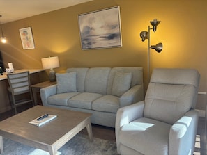 A living room with a sofa, armchair, coffee table, lamp, and artwork on the wall. - SR-15 Ground Floor Gulf Front (Siesta Key)