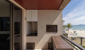 Un balcon donnant sur la plage, un mur recouvert de carreaux et un banc.
