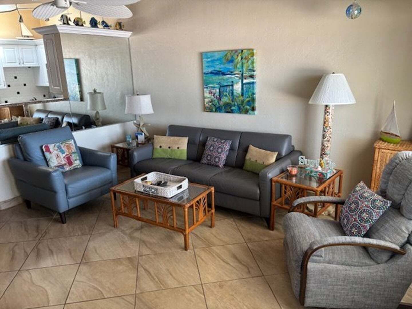 Un salon avec un canapé, des fauteuils, une table basse et un tableau accroché au mur.