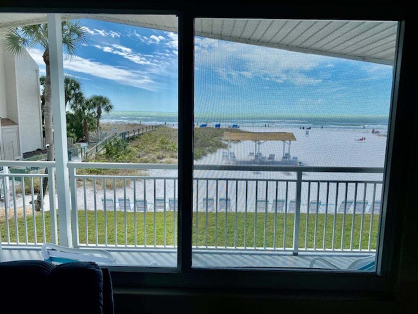 Een balkon met uitzicht op een strand en een overdekt zitgedeelte.