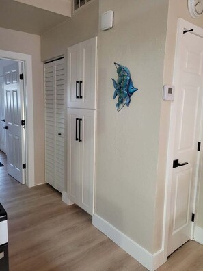 Ein Flur mit weißen Türen, einer Fischdekoration an der Wand und einem Thermostat.