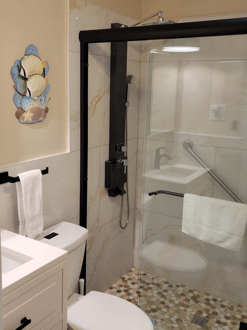 A modern bathroom with a glass-enclosed shower, a white toilet, and a sink.