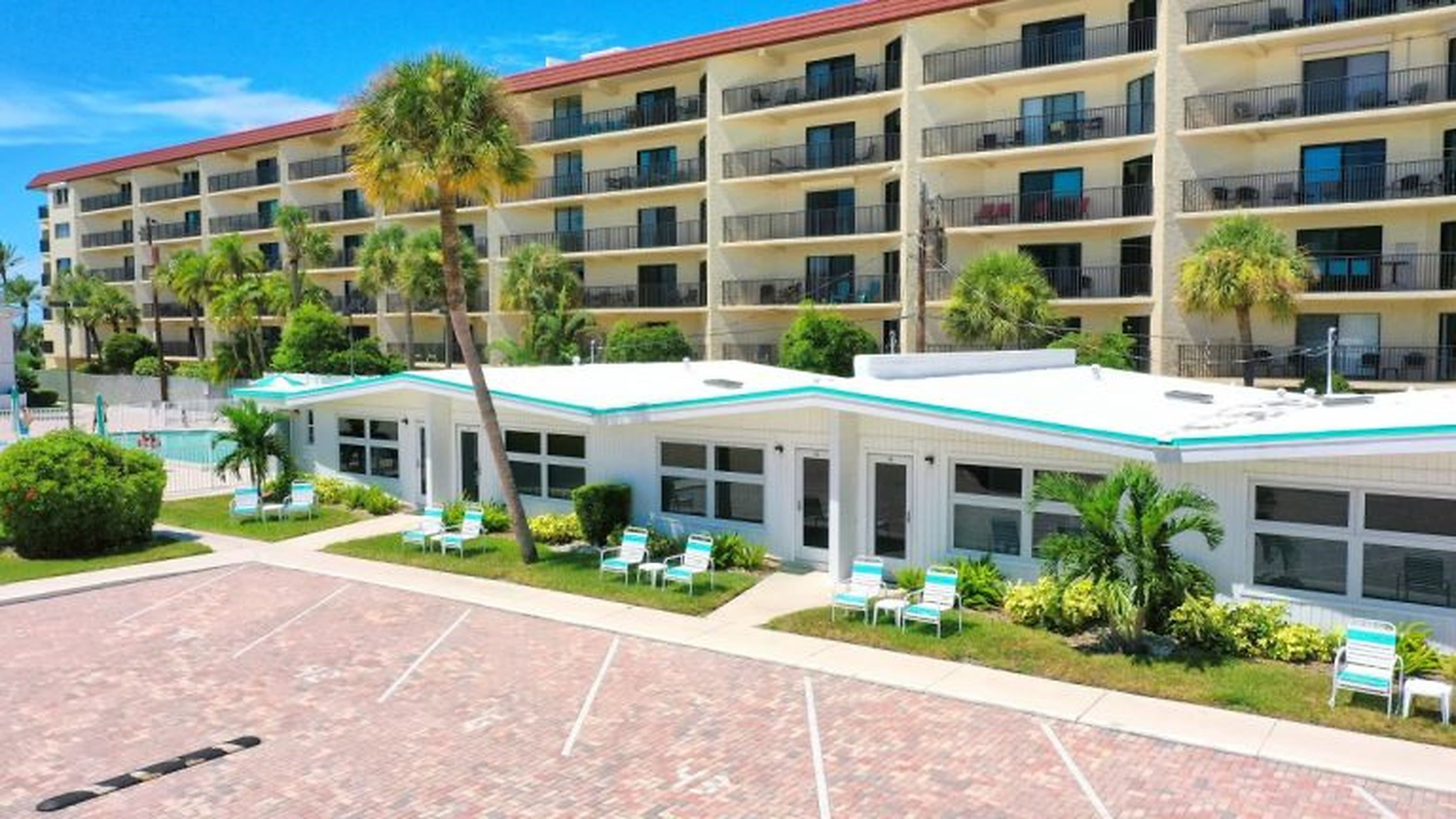 Un hôtel à plusieurs étages doté de balcons, d’un espace piscine et d’un espace extérieur couvert aménagé en salon.