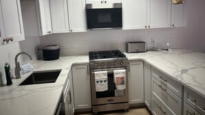 A modern kitchen with white cabinets, a stainless steel stove, a microwave, and a toaster. - SR-23 Lovely 1/1 Unit (Siesta Key)