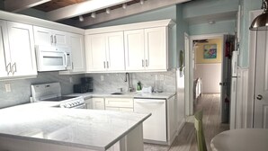 A kitchen with white cabinets, a built-in oven, a microwave, and a coffee maker. - SR- North Court Unit (Siesta Key)