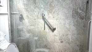 A bathroom with a glass-enclosed shower, a toilet, and a sink. - SR- North Court Unit (Siesta Key)