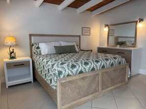 Une chambre à coucher avec un lit, des tables de chevet, un miroir et une lampe.