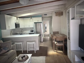 Eine moderne Küche mit weißen Schränken, einer zentralen Kochinsel und einem Essbereich mit Holztischen und einem Tisch.