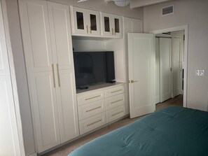 Ein Schlafzimmer mit einem Bett, einem Kleiderschrank mit Schubladen und einem Fernseher.
