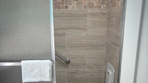 Baño con ducha, inodoro y perchero para toallas.