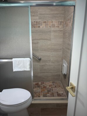 Ein Badezimmer mit Dusche, Toilette und Handtuchhalter.