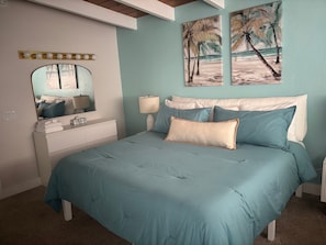 Ein Schlafzimmer mit Bett, Kommode, Spiegel und Wandbildern.