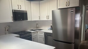 Una cocina moderna con armarios blancos, electrodomésticos de acero inoxidable y encimera de mármol.