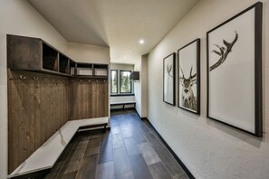 A hallway with a wooden bench, framed artwork, and a view of the outdoors. - Hot Tub | Mountain Views | Walk To Downtown (Winter Park)