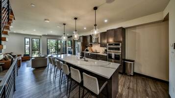 A modern kitchen with a large island, stainless steel appliances, and pendant lighting.