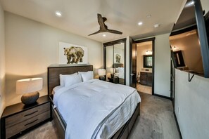 A hotel room with a bed, bedside tables, a ceiling fan, and a large mirror. - Hot Tub | Mountain Views | Walk To Downtown (Winter Park)