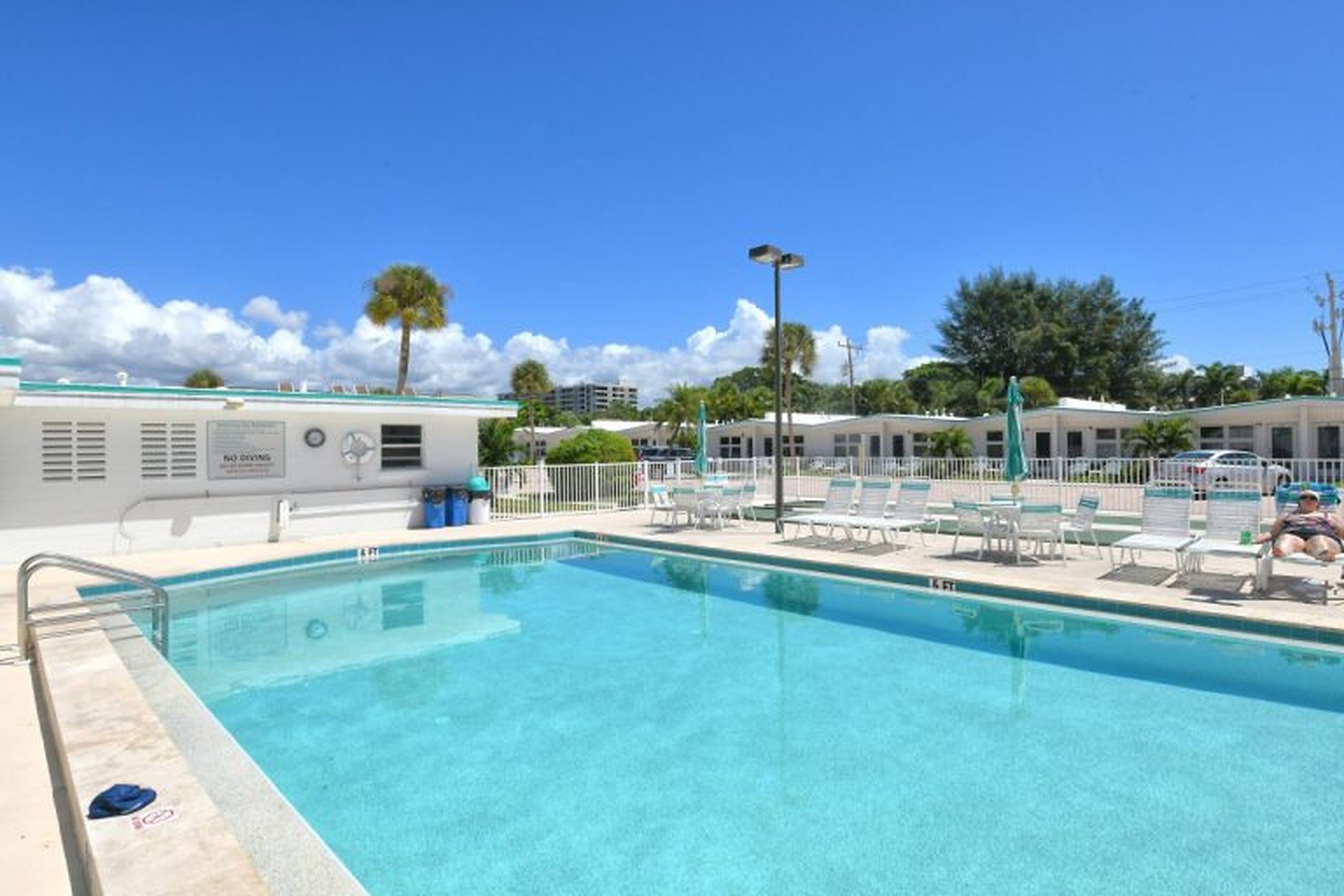 A swimming pool with lounge chairs and a building with a sign.