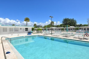 A swimming pool with lounge chairs and a building with a sign. - SR-34 - 1BR Siesta Key condo with king bed, sleep sofa, courtyard view. (Siesta Key)
