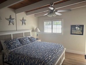 A bedroom with a bed, a ceiling fan, a window with blinds, and wall decorations. - SR-34 - 1BR Siesta Key condo with king bed, sleep sofa, courtyard view. (Siesta Key)