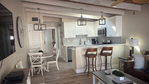 Une cuisine moderne avec des meubles blancs, un îlot central doté de tabourets et des luminaires suspendus.