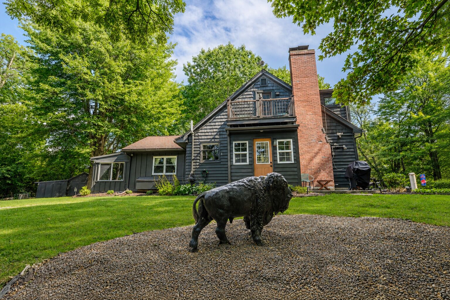 A two-story house with a chimney, a front porch, and a gravel driveway.