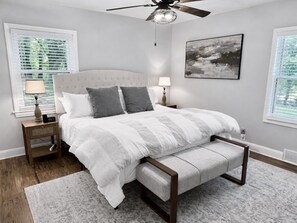 A bedroom with a bed, bedside tables, a ceiling fan, and artwork on the wall.