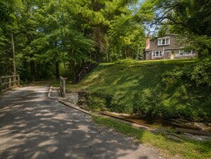 A two-story house with a paved driveway and a wooden staircase leading to the entrance.