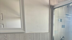 Ett badrum med ett vitt handfat, en toalett och en duschkabin med glasväggar.