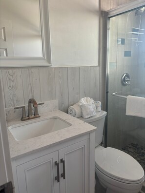 A bathroom with a white sink, a toilet, and a glass shower enclosure. - SR-40, Lovely Courtside Unit (Siesta Key)