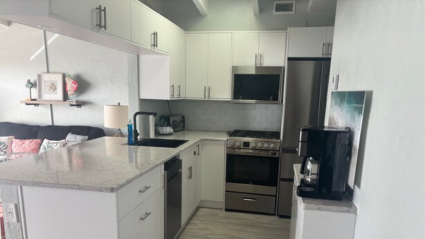 A modern kitchen with white cabinets, stainless steel appliances, and a marble countertop. - SR-41 Siesta Key 1BR condo with king bed, sleeper sofa, and courtyard views. (Siesta Key)