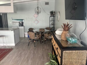 A modern kitchen with a dining area, featuring a round table, wicker chairs, and a bar area with a decorative glass pitcher. - SR-41 Siesta Key 1BR condo with king bed, sleeper sofa, and courtyard views. (Siesta Key)