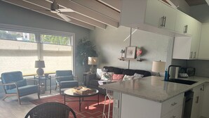 A modern kitchen with white cabinets, a central island, and a dining area with wicker chairs. - SR-41 Siesta Key 1BR condo with king bed, sleeper sofa, and courtyard views. (Siesta Key)