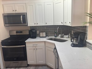 A kitchen with white cabinets, a microwave, a stove, a coffee maker, and a sink. - SR- 44 1BR Siesta Key apartment with king bed and sleeper sofa. (Siesta Key)