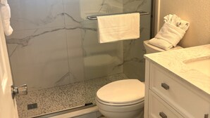 Kylpyhuoneessa on lasiseinällä varustettu suihku, wc, marmoritasoinen pesuallas ja pyyheteline.