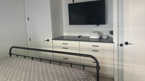 A bedroom with a bed, a TV mounted on a wall, a bedside table, and a wardrobe. - SR-45 - 1BR Siesta Key condo with king bed, sleep sofa, and courtyard views. (Siesta Key)