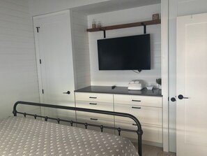 A bedroom with a bed, a TV mounted on a wall, a bedside table, and a wardrobe. - SR-45 - 1BR Siesta Key condo with king bed, sleep sofa, and courtyard views. (Siesta Key)