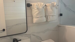 A bathroom with a white sink, a mirror, a toilet, and a towel rack with towels. - SR-45 - 1BR Siesta Key condo with king bed, sleep sofa, and courtyard views. (Siesta Key)