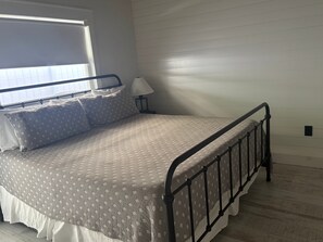 A single bed with a metal frame, a bedside table with a lamp, and a window with blinds. - SR-45 - 1BR Siesta Key condo with king bed, sleep sofa, and courtyard views. (Siesta Key)