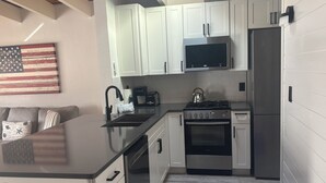 A modern kitchen with white cabinetry, a stainless steel refrigerator, a gas stove, and a microwave. - SR-45 - 1BR Siesta Key condo with king bed, sleep sofa, and courtyard views. (Siesta Key)