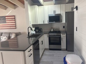 A modern kitchen with white cabinetry, a stainless steel refrigerator, a gas stove, and a microwave. - SR-45 - 1BR Siesta Key condo with king bed, sleep sofa, and courtyard views. (Siesta Key)