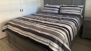 A bedroom with a bed, a nightstand, a wardrobe, and a painting on the wall. - SR-50 -1BR 1BA Courtyard Unit (Siesta Key)