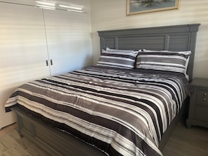 A bedroom with a bed, a nightstand, a wardrobe, and a painting on the wall. - SR-50 -1BR 1BA Courtyard Unit (Siesta Key)