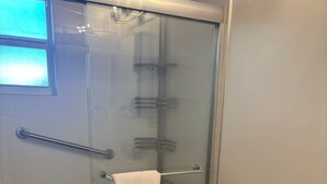 A bathroom with a glass-enclosed shower, a toilet, and a sink. - SR-50 -1BR 1BA Courtyard Unit (Siesta Key)