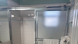 A bathroom with a glass-enclosed shower, a toilet, a sink, and a mirror. - 1BR Siesta Key condo with king bed, Murphy bed, courtyard views. (Siesta Key)
