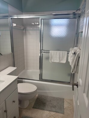 Ein Badezimmer mit Duschkabine, Toilette, Waschbecken und Spiegel.