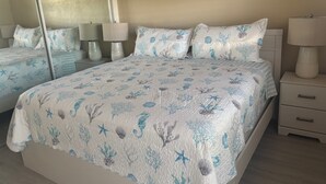 Ein Schlafzimmer mit einem Bett, Nachttischen, Lampen und einem großen Spiegel.