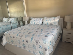 A bedroom with a bed, bedside tables, lamps, and a large mirror. - 1BR Siesta Key condo with king bed, sleep sofa, and courtyard views. (Siesta Key)