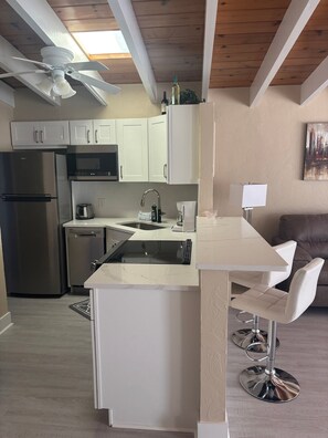A modern kitchen with a built-in island, stainless steel appliances, and a ceiling fan. - 1BR Siesta Key condo with king bed, sleep sofa, and courtyard views. (Siesta Key)