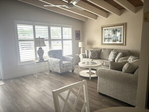 A living room with a patterned armchair, a sofa, a coffee table, and a lamp. - Cozy 1BR Siesta Key apartment with courtyard view (Siesta Key)